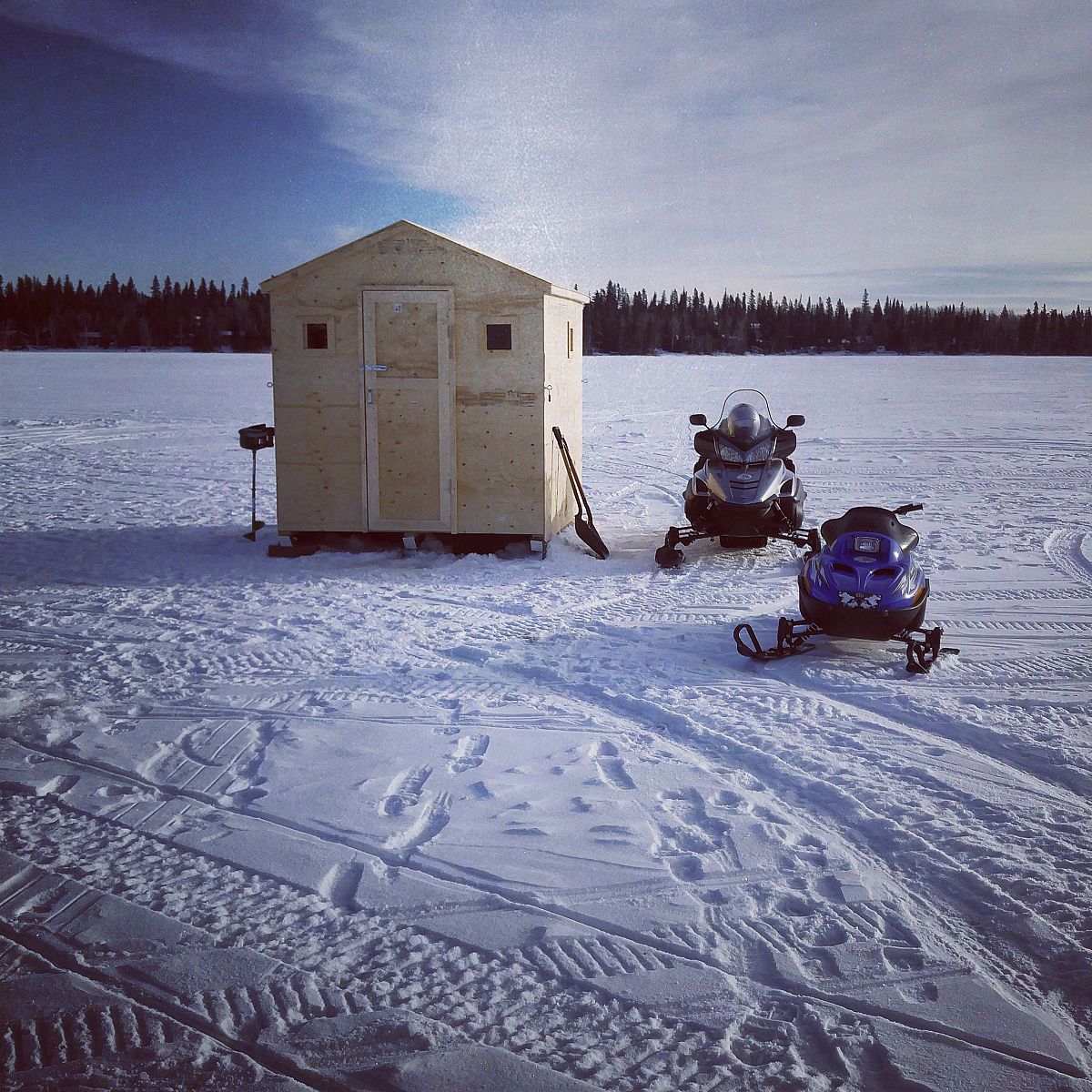 The sleds resting by the ice fishing shack